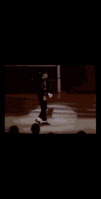 a man in a suit is dancing on a stage in front of a microphone