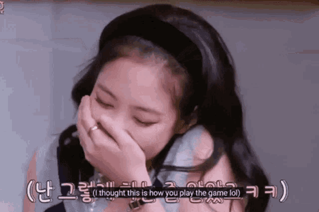 a young girl is covering her mouth with her hand while laughing .