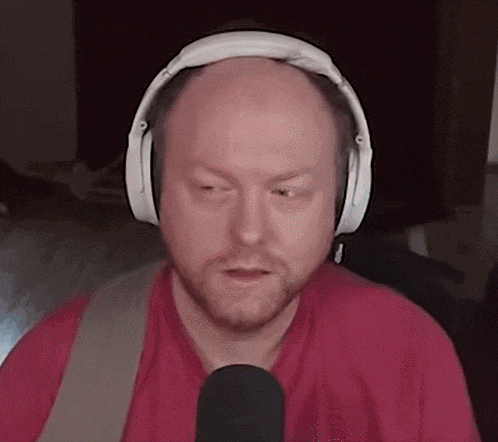 a bald man with a beard is wearing headphones and a red shirt .