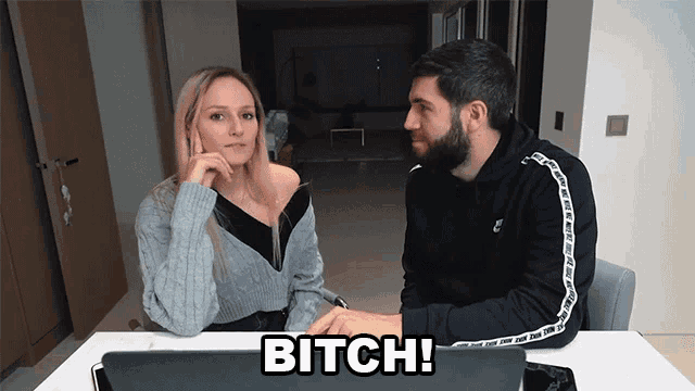 a man and a woman are sitting at a table with the word bitch written on it