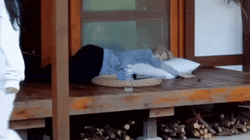 a woman is laying on a wooden deck with a pillow and a bottle of water on it .