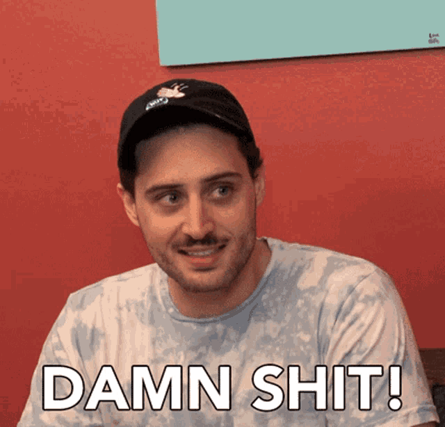 a man wearing a hat and a tie dye shirt says " damn shit "