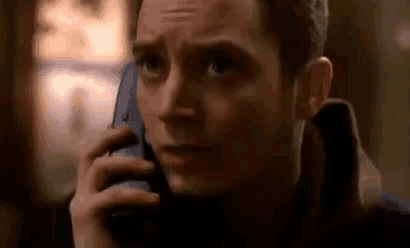 a man is talking on a cell phone with a serious look on his face .