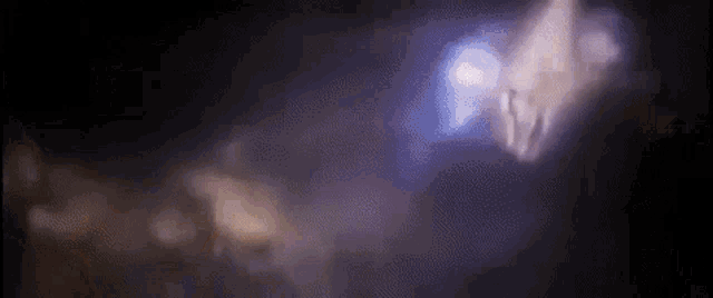 a blurry picture of a person standing in the dark with a purple light behind them .