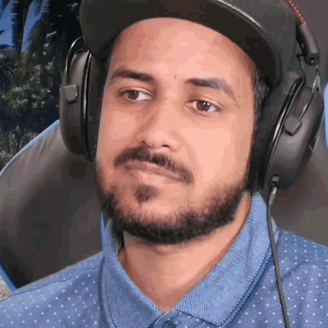 a man with a beard wearing headphones and a baseball cap