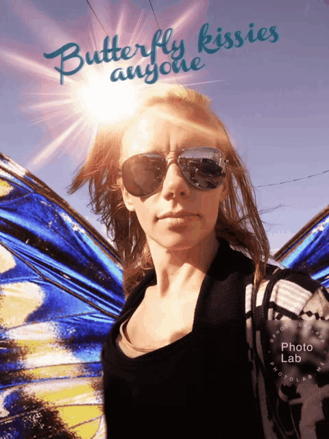 a woman wearing sunglasses stands in front of a butterfly kisses anyone sign