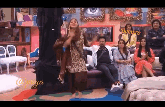 a woman is dancing in front of a group of people with the name bumbro on the bottom right