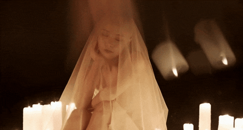 a woman with a veil on her head is surrounded by candles