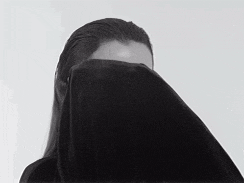 a woman with rhinestones on her face is covering her face with a black blanket