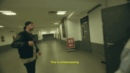 a man walking down a hallway with the words " this is embarrassing " on the bottom