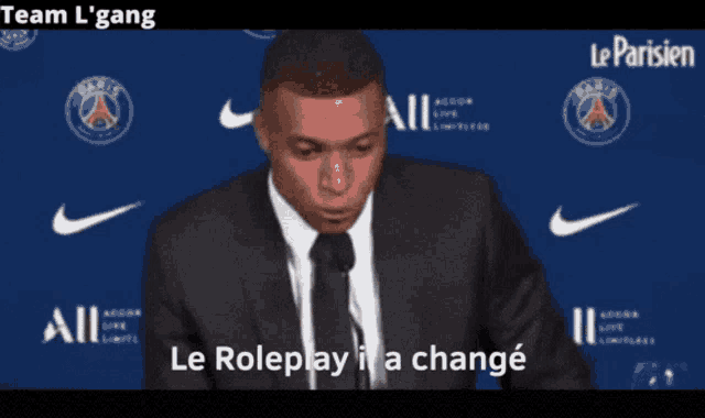 a man in a suit and tie speaking into a microphone with the words le roleplay il a change
