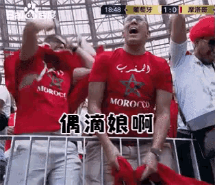 a man wearing a red shirt that says morocco stands in a crowd