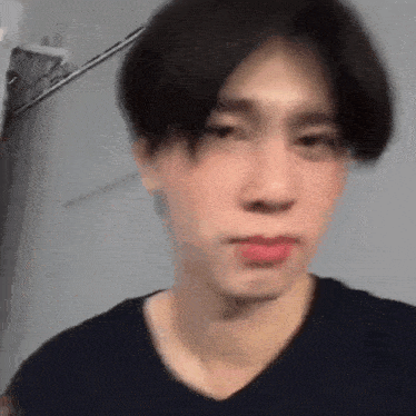 a close up of a man 's face with a blurry background . he is wearing a black shirt and red lipstick .