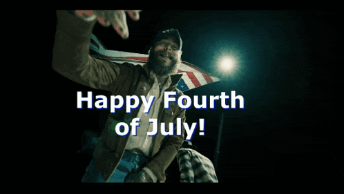 a man with a beard is waving in front of an american flag and says " happy fourth of july "