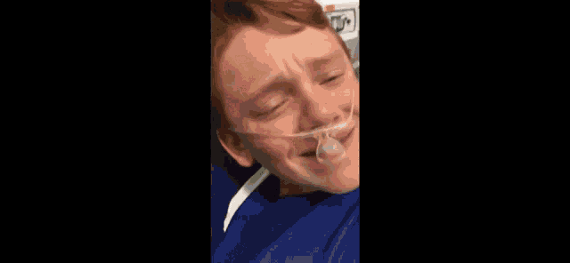 a young boy wearing an oxygen mask in a hospital bed