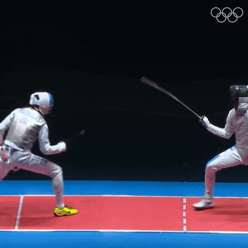 two fencers are fighting on a red court with the olympics logo in the background