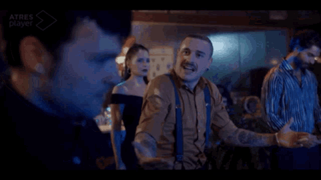 a group of people are standing in a dark room and one of them has a tattoo on his arm