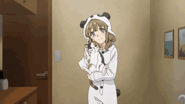 a girl in a panda costume holds a cat in her arms