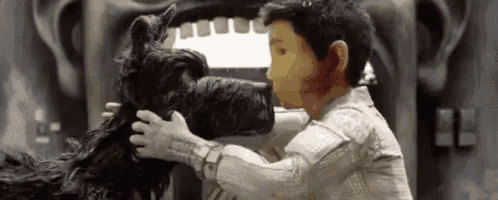 a man and a dog are standing next to each other in front of a statue .
