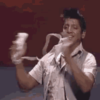 a man in a white shirt is holding a remote control in his hands .