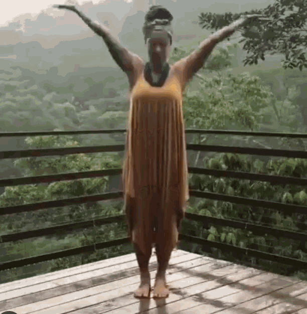 a woman in a dress is standing on a deck with her arms outstretched .