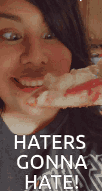 a woman eating a slice of pizza with the words haters gonna hate on the bottom