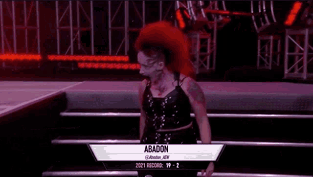 a woman with red hair is standing on a stage with a sign that says abadon .
