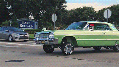 a green car is driving past a sign that says lake bullard