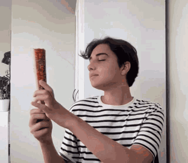 a man in a striped shirt is holding a brush that says ' sally ' on it