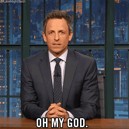 a man in a suit and tie is sitting at a desk and says oh my god