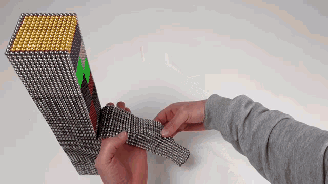 a person is holding a stack of magnets and a piece of metal