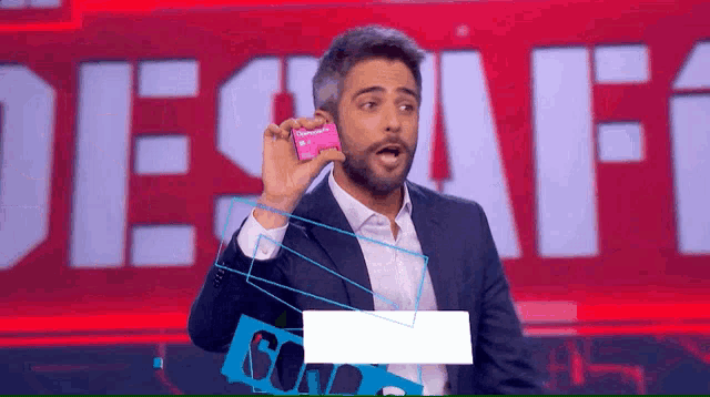 a man in a suit is holding a credit card in front of a red background that says desafio