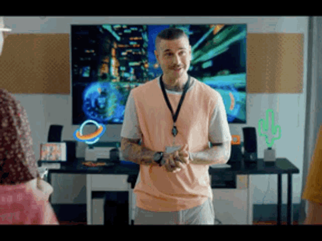 a man in a pink shirt is standing in front of a computer monitor