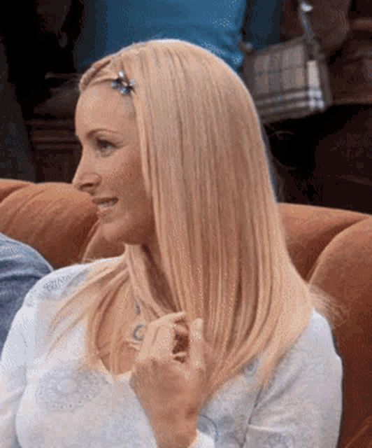 a blonde woman is sitting on a couch with a hair clip in her hair