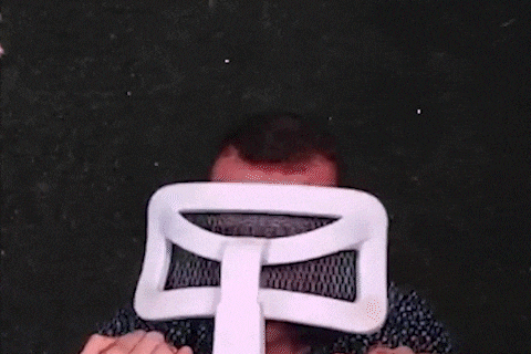 a man in a blue shirt is holding a white chair in his hands .