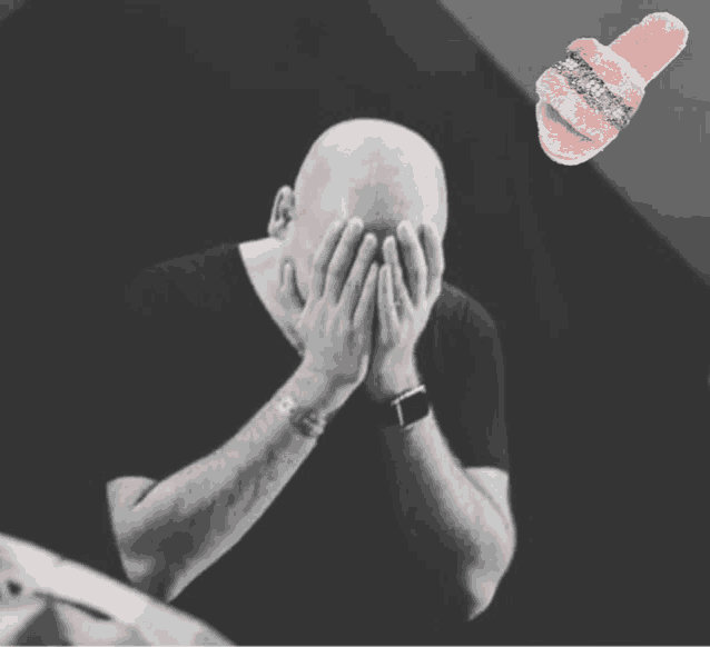 a bald man covering his face with his hands next to a pink slipper with rhinestones on it