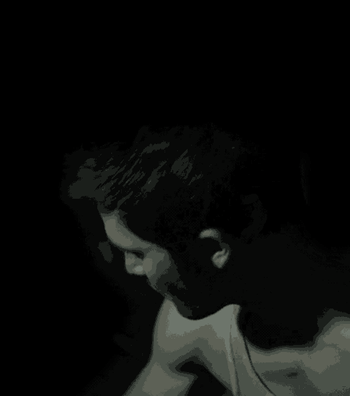 a man without a shirt is standing in the dark