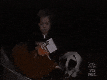 a man in a suit is eating a piece of ice cream in the dark .
