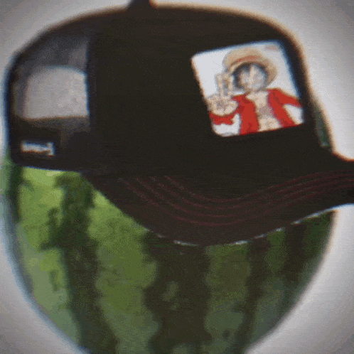 a hat with a picture of luffy on it sits on top of a watermelon