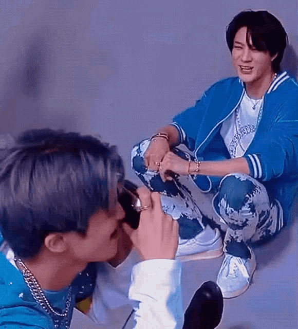 a man in a blue jacket is taking a picture of another man .