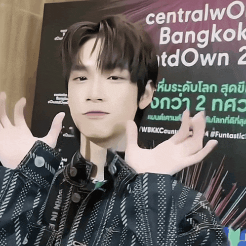 a young man stands in front of a sign that says centralworld bangkok downtown 2