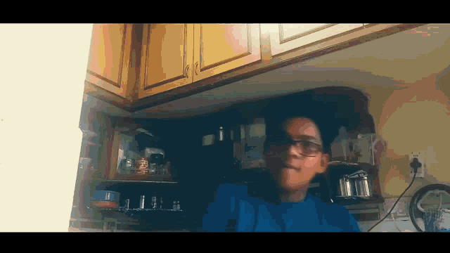 a person wearing glasses is sitting in a kitchen