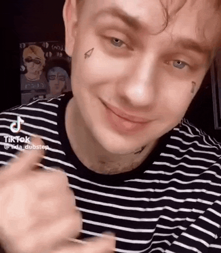a young man with a tattoo on his face is smiling .
