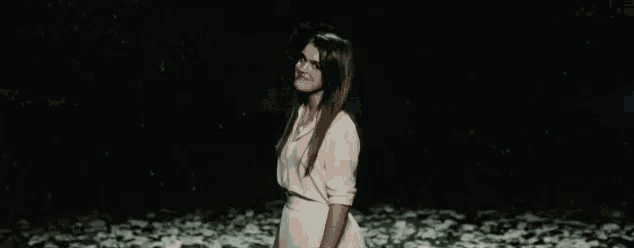 a woman in a white dress is standing in front of a body of water .