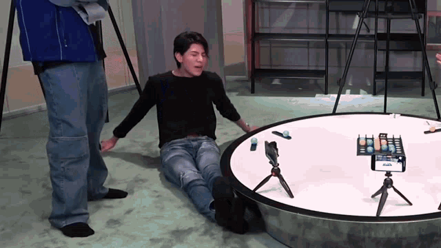 a man is laying on the floor in front of a table with a phone on it that says ' a ' on it