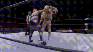 two women are wrestling in a wrestling ring with a referee watching .