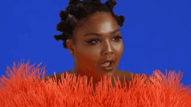 a woman with white eye shadow on her eyes is surrounded by orange fur