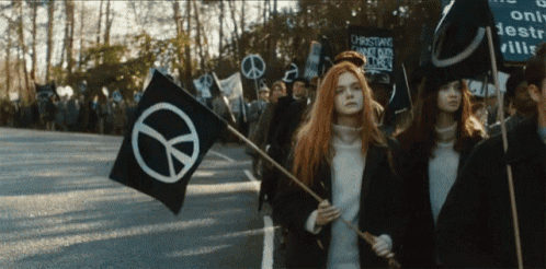 a group of people marching down a street with a peace sign on their flag