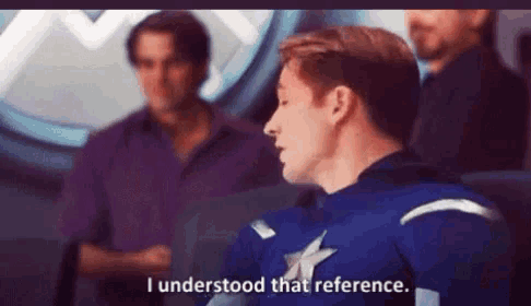 a man in a captain america uniform is talking to a group of men .