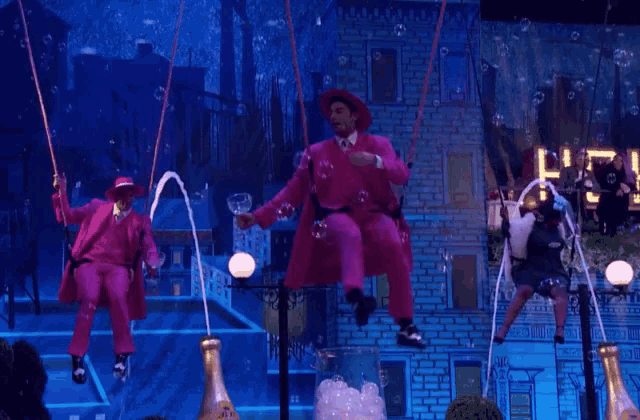 a man in a pink suit is sitting on a swing with bubbles coming out of it